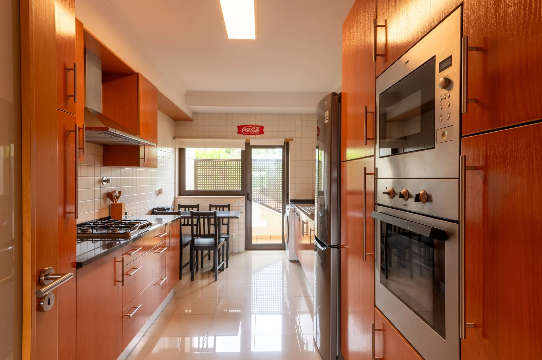 A kitchen with wooden cabinetry, built-in appliances, and a dining table by the window.