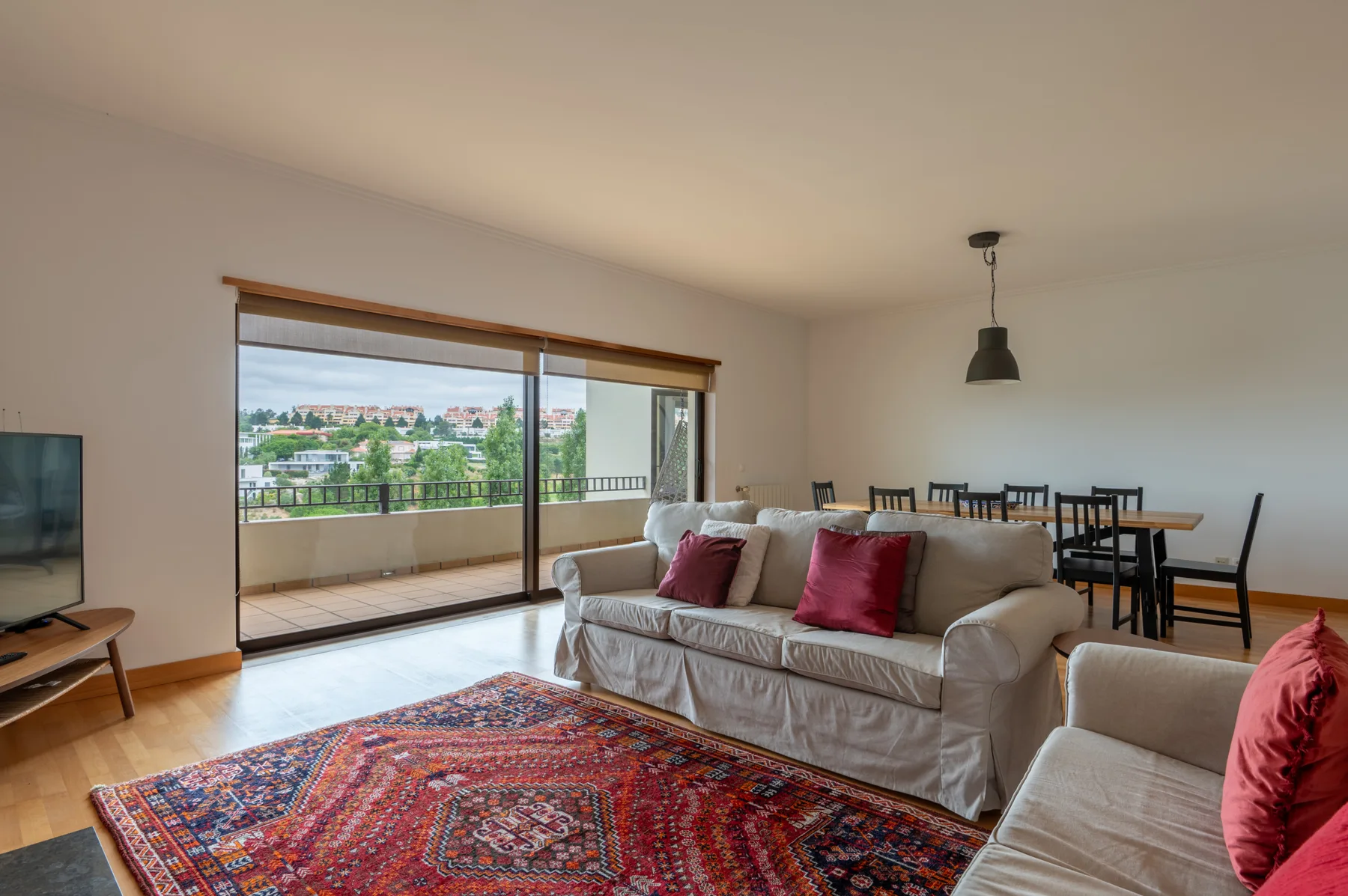 A living room with seating and a large patterned rug beside a balcony.