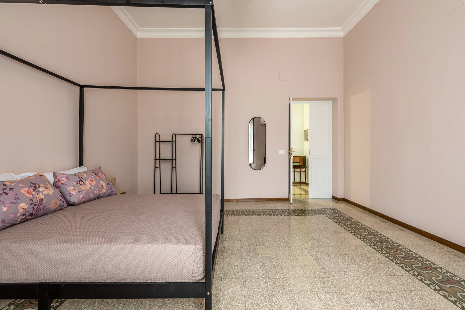 Un dormitorio con una cama y una puerta abierta que da a otra habitación.