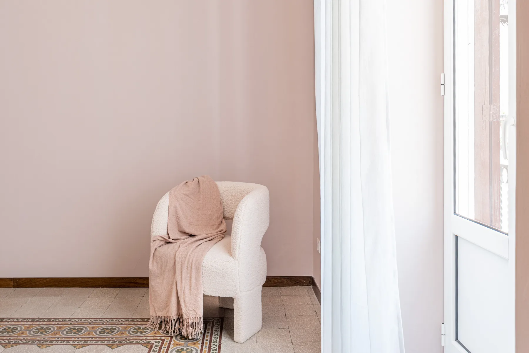Una zona de asientos con una silla cubierta junto a una puerta de vidrio luminosa.