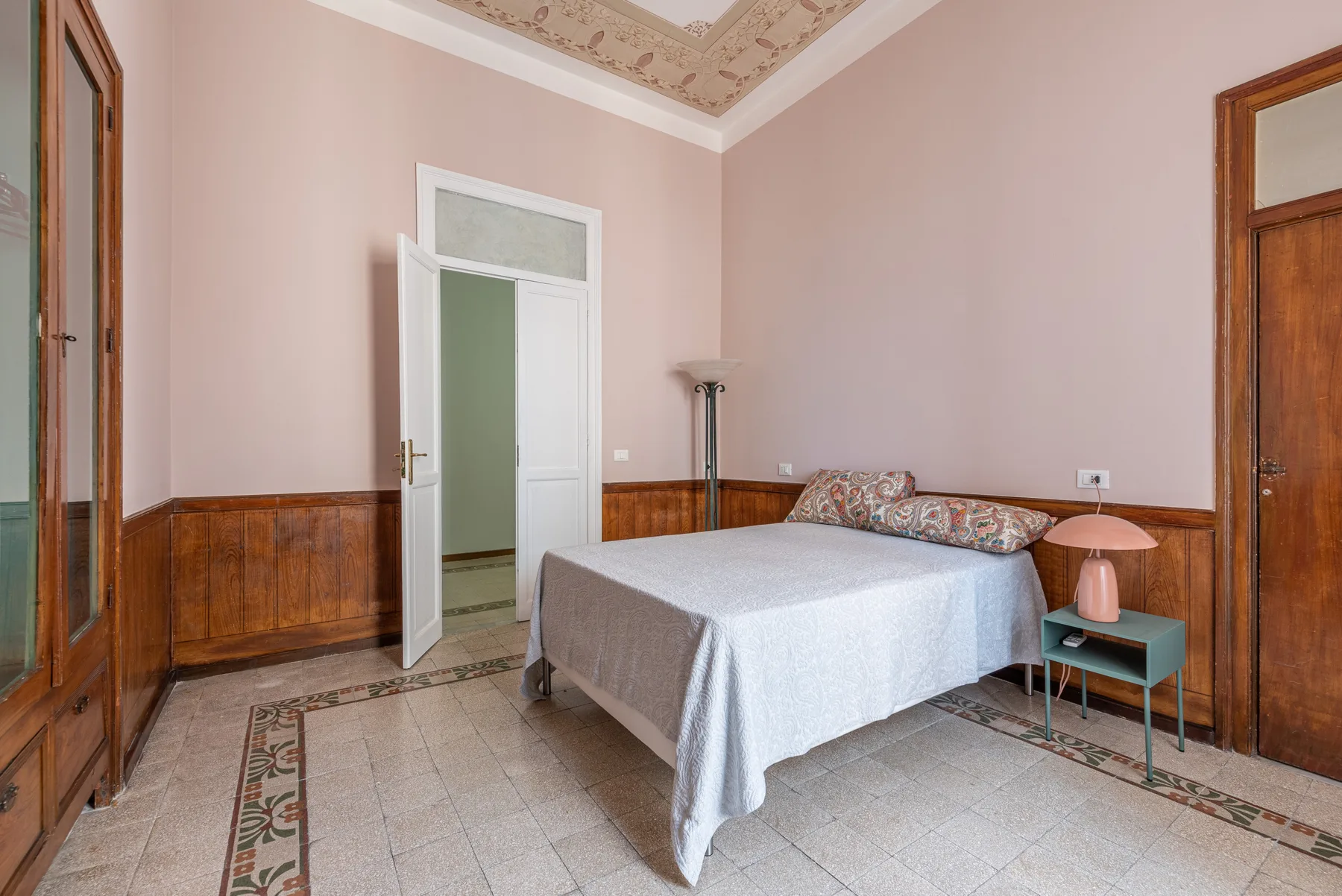 A bedroom with a bed and a small bedside table.