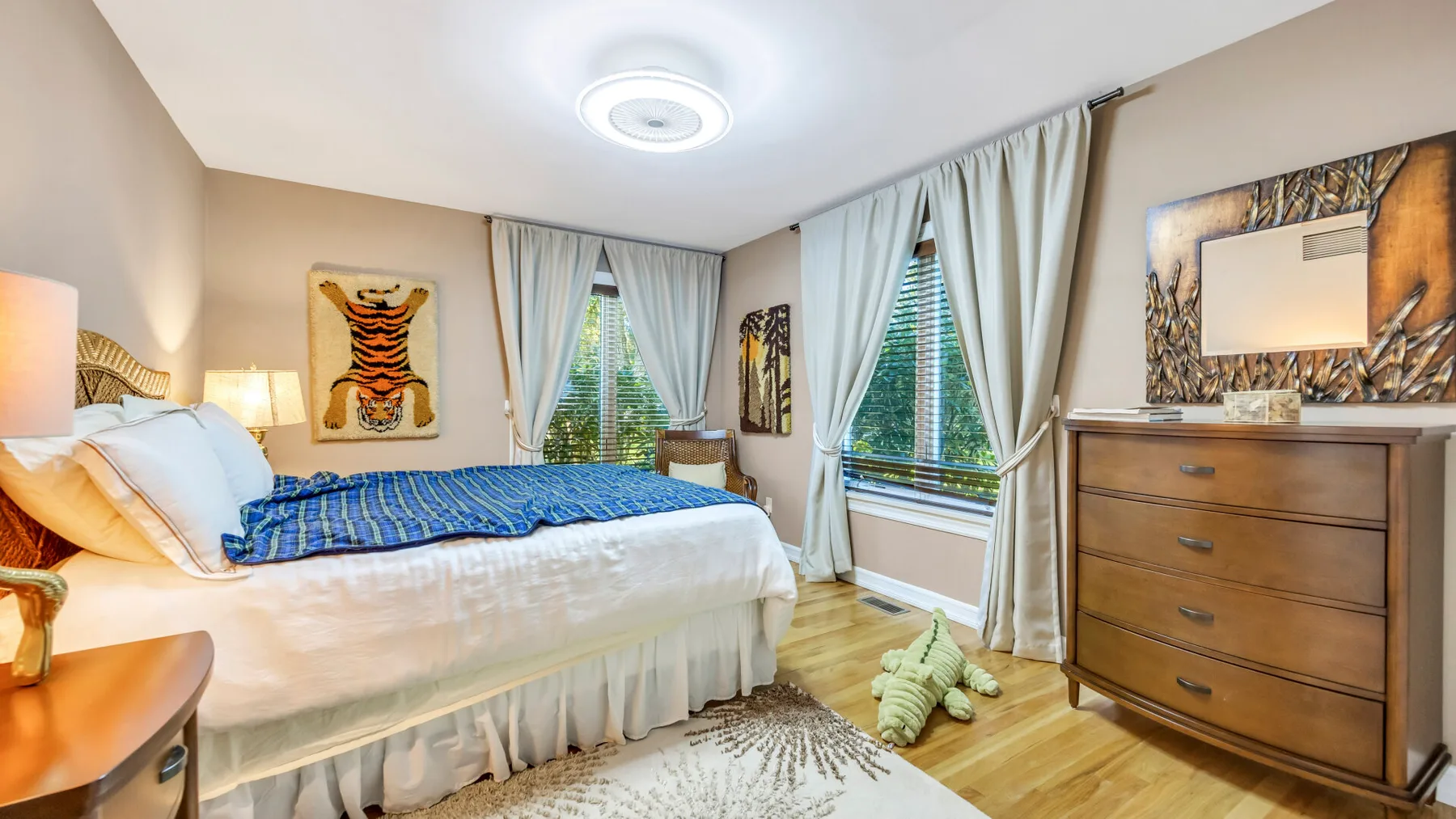 Un dormitorio con una cama, una cómoda de madera y ventanas con cortinas.