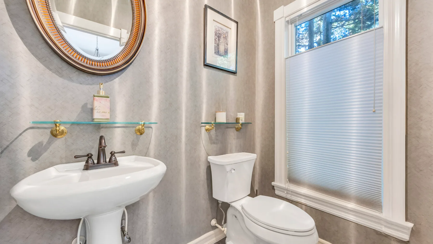 Un baño con lavabo, inodoro y una ventana con la persiana cerrada.