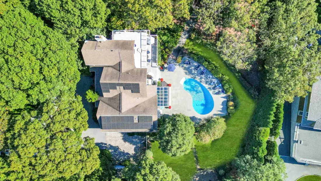 Vista aérea de una casa, una piscina y vegetación alrededor.