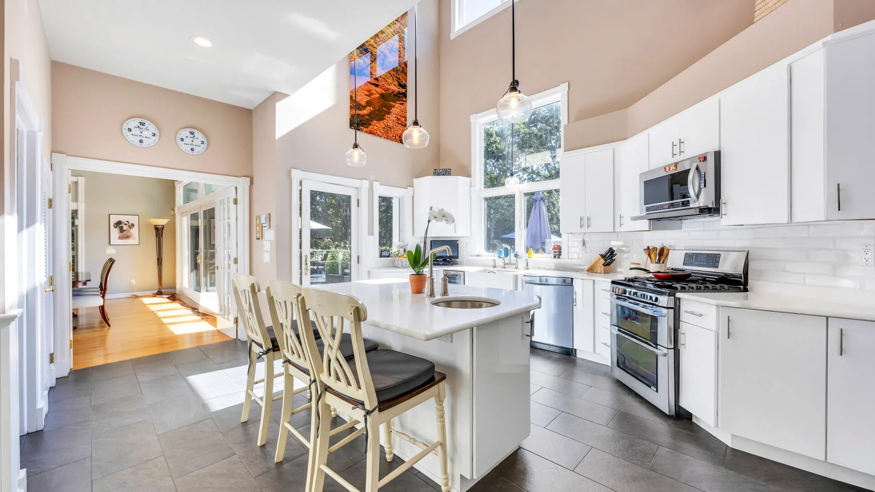 Una cocina luminosa con una isla central y gabinetes blancos.