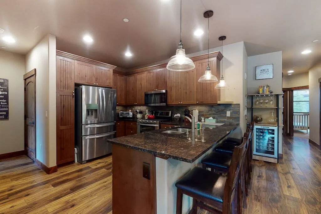A spacious kitchen with a central island, dark countertops, and wooden cabinets.