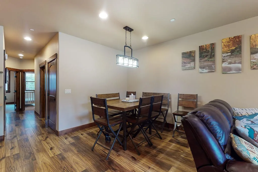 A dining area with a wooden table and chairs beside a living room.