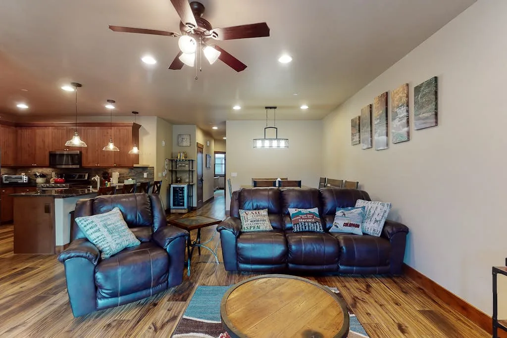 An open-plan living room and kitchen with leather seating and a dining table.