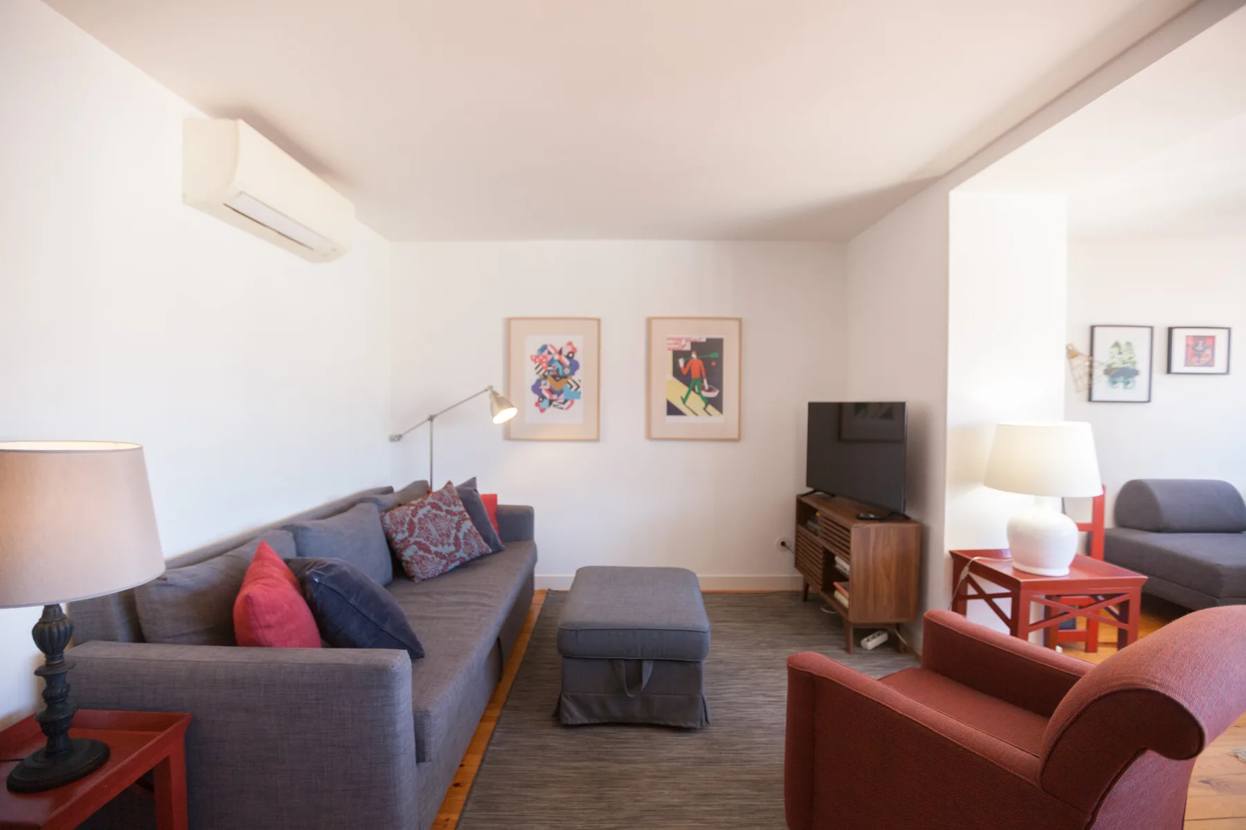 Una sala de estar con asientos, un televisor y cuadros en la pared.