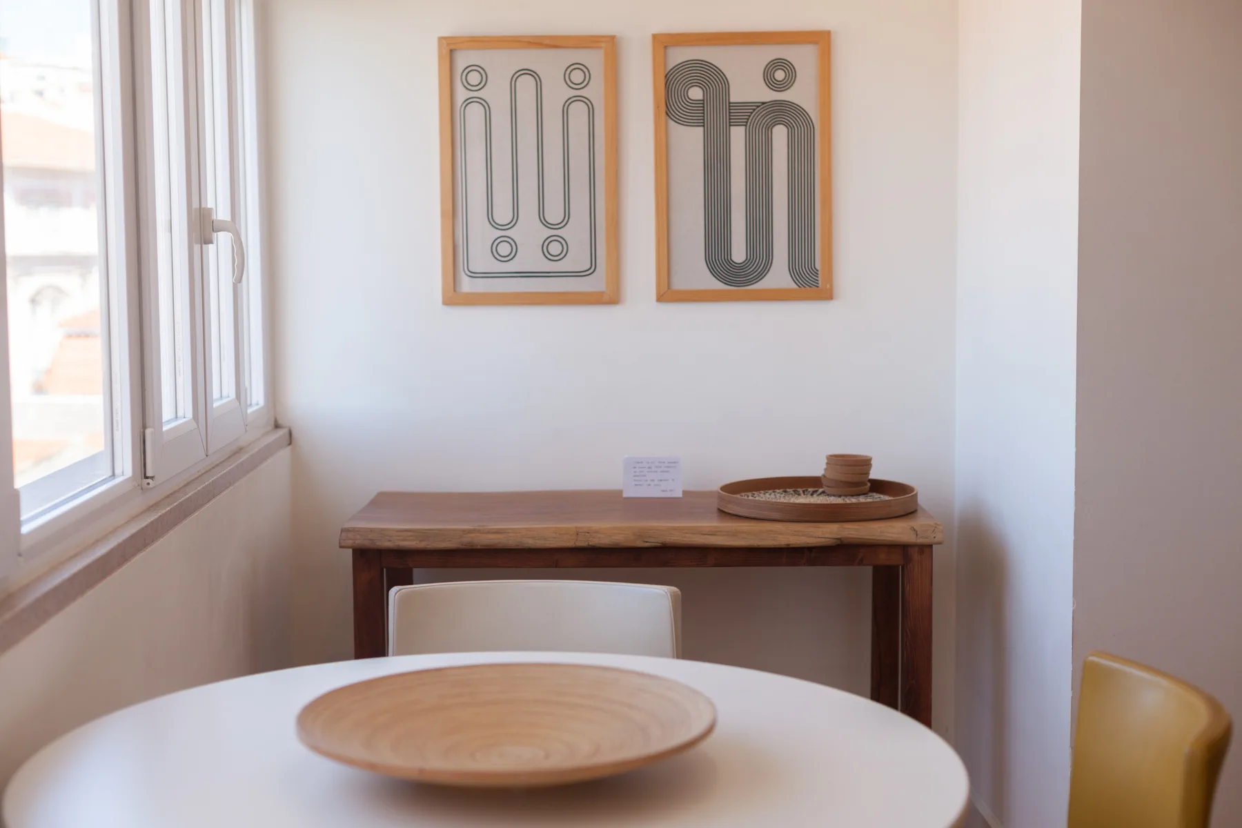 Comedor con una mesa redonda, una consola de madera y arte enmarcado.