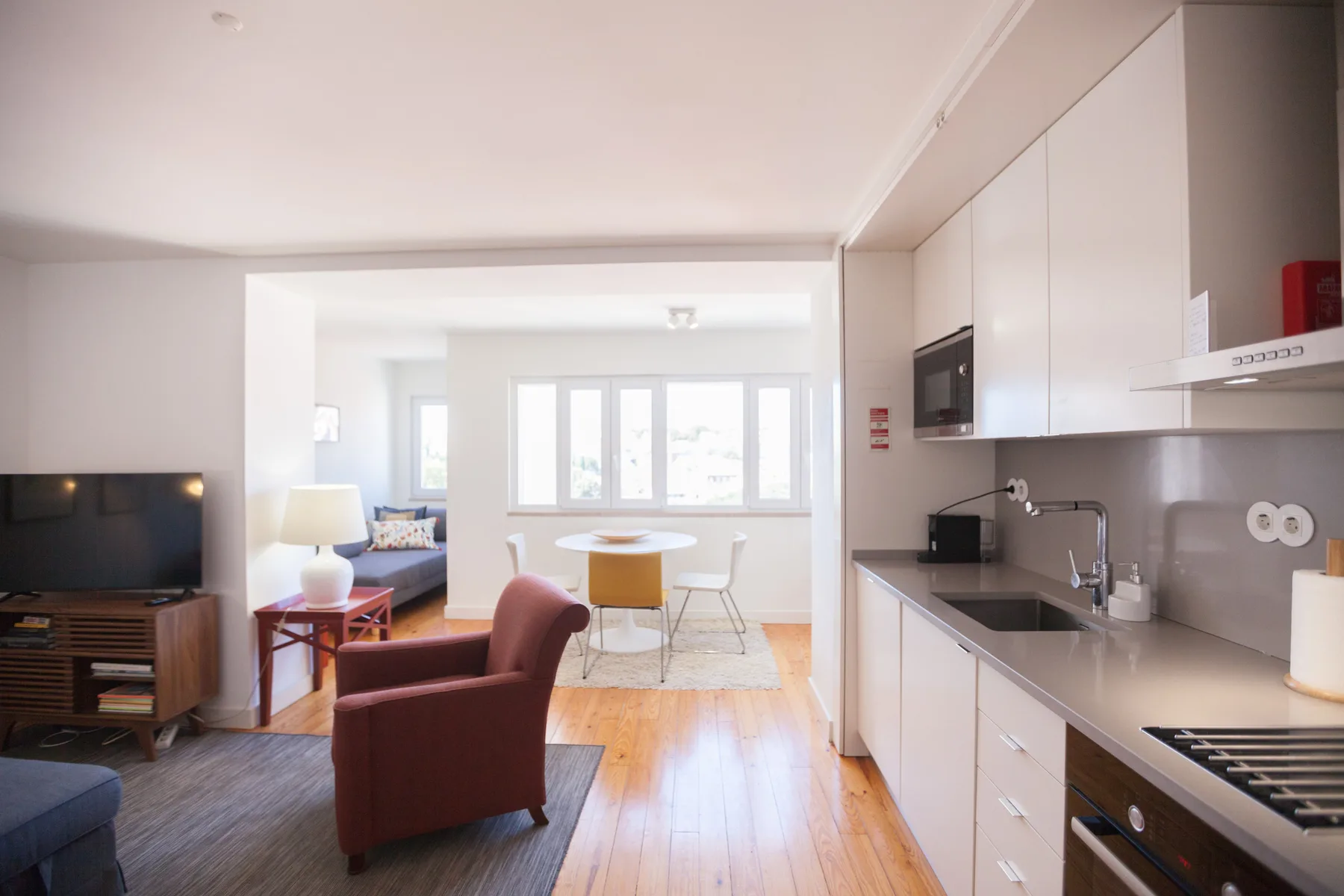 Una sala de estar abierta a la cocina, con una mesa de comedor junto a las ventanas.