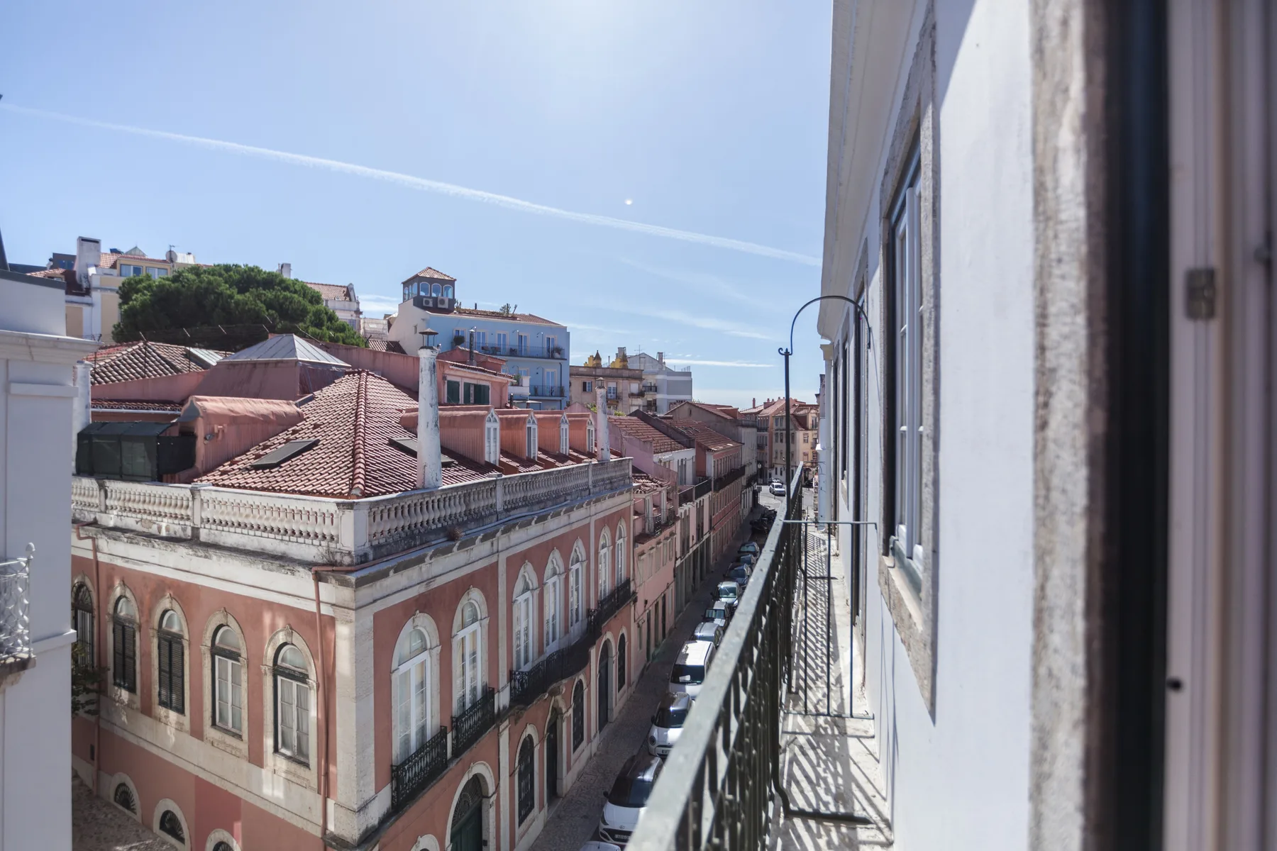 Desde un balcón estrecho se ven una calle de la ciudad y tejados cercanos.