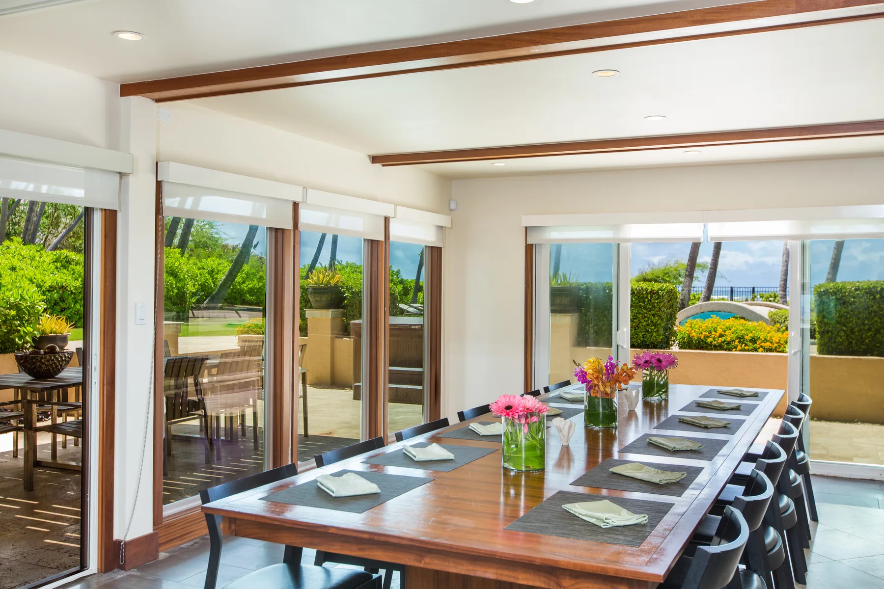 A bright dining room with a long table set beside large windows.