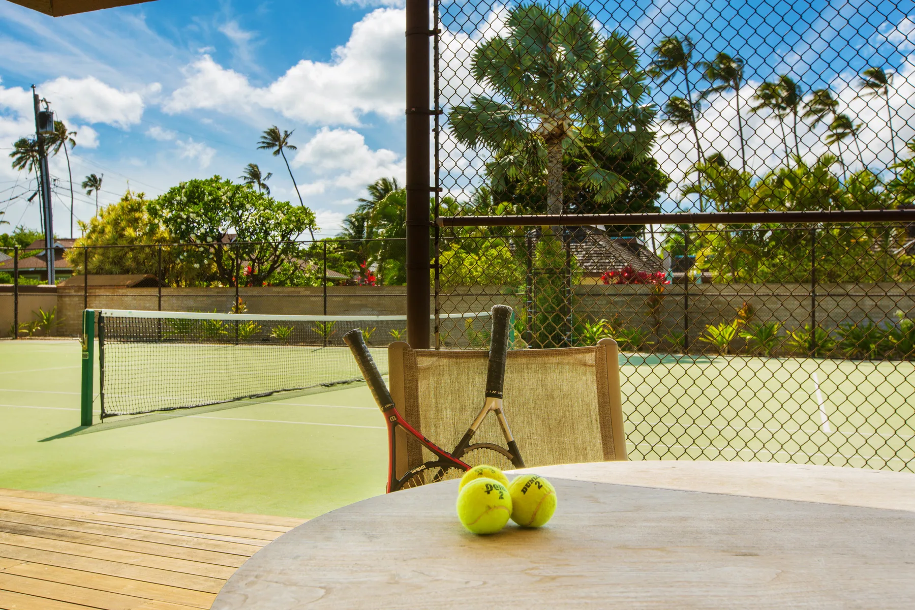 Una cancha de tenis con dos pelotas y raquetas junto a una mesa.