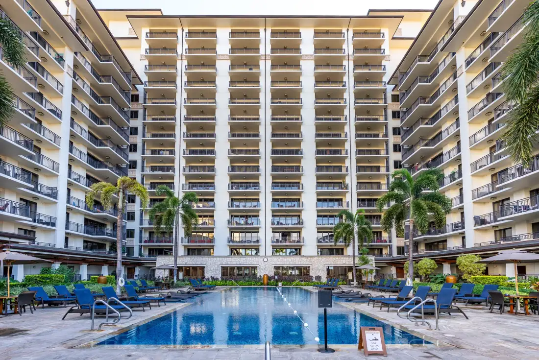 Una piscina está en un patio rodeado por un edificio de varios pisos.
