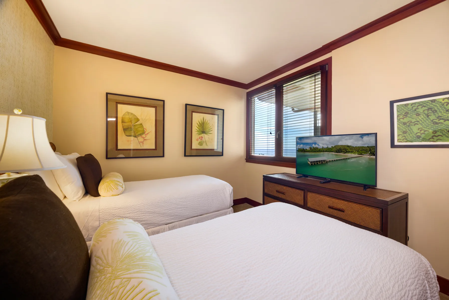 Un dormitorio con dos camas y un televisor sobre una cómoda de madera.