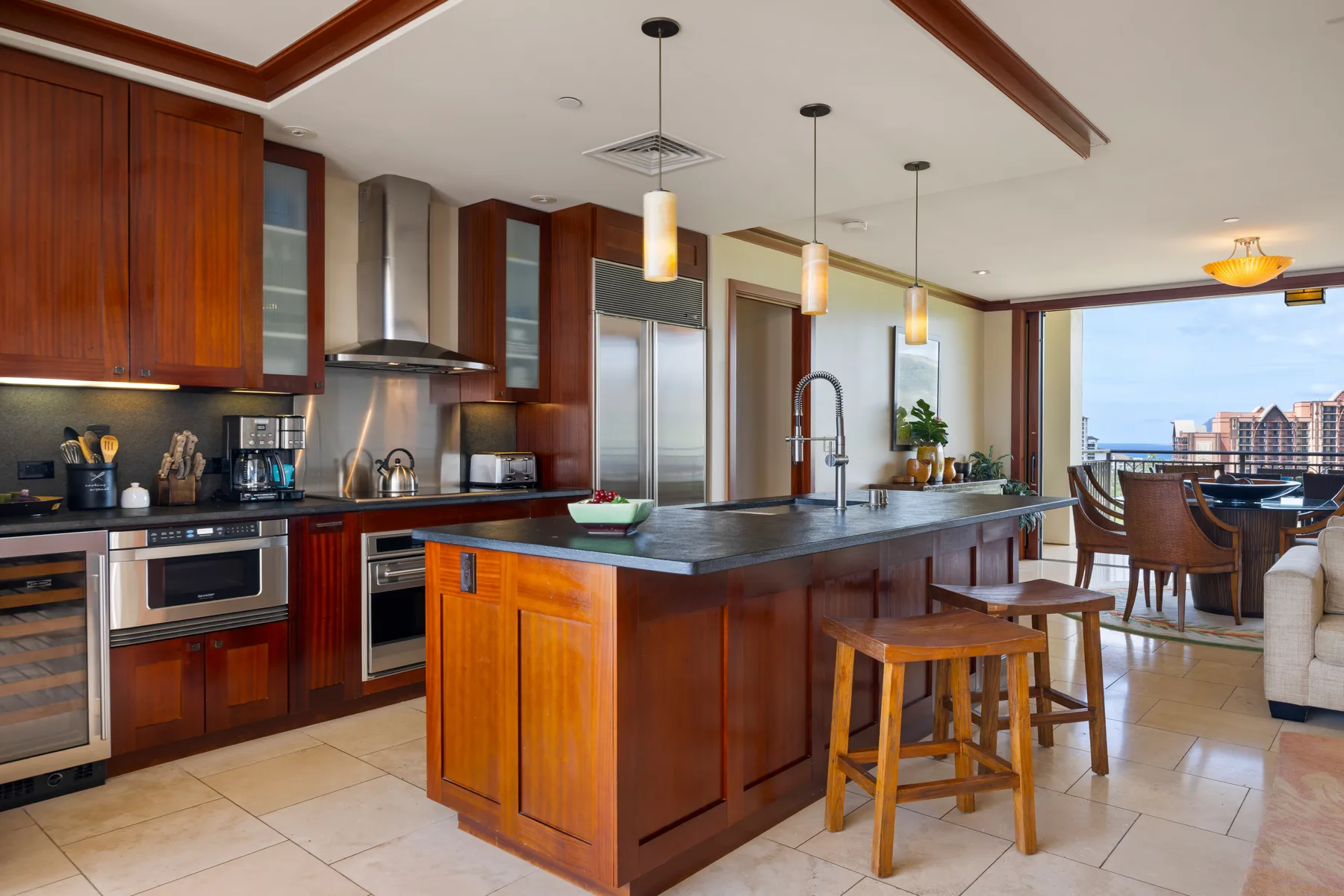 Una cocina con una isla central y un comedor junto a las ventanas.