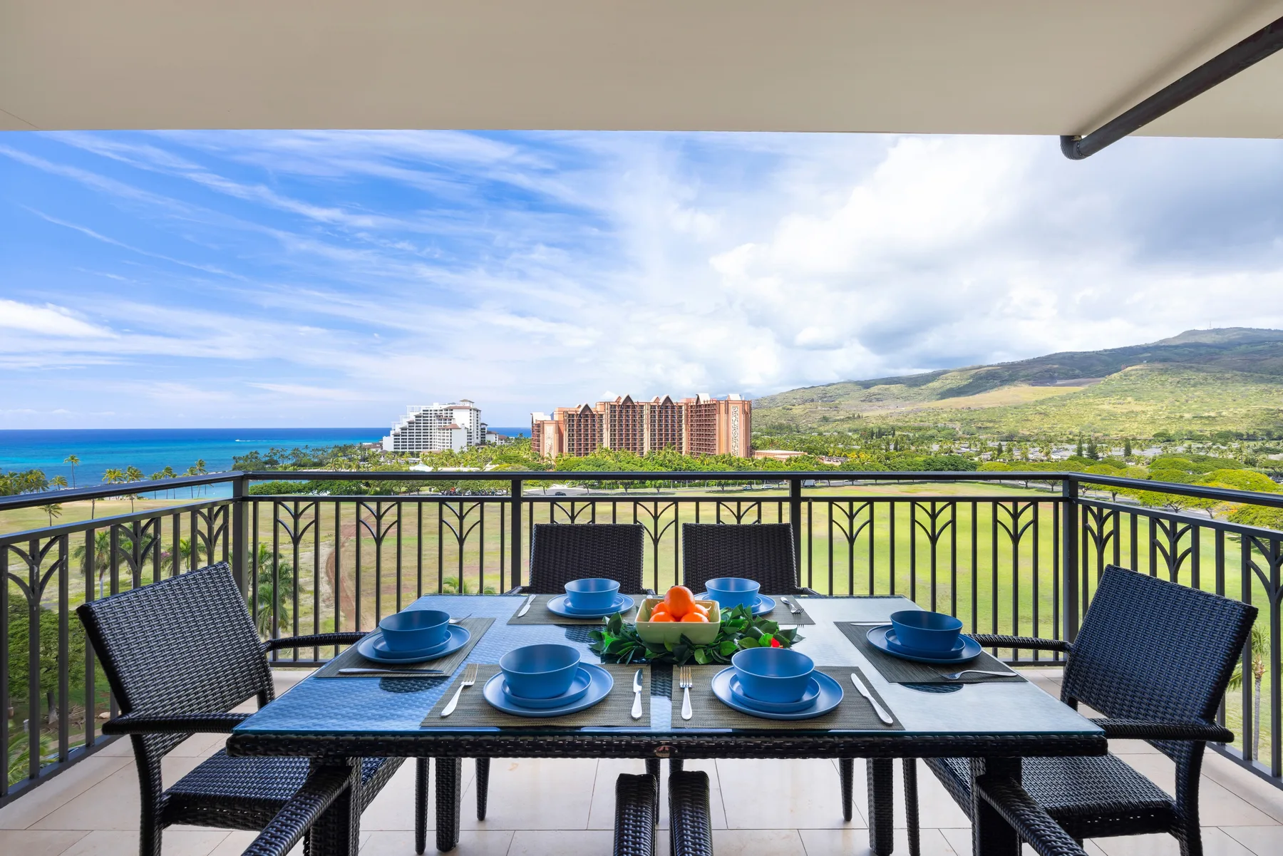 Una zona de comedor en el balcón ofrece vistas al mar y a las colinas verdes.