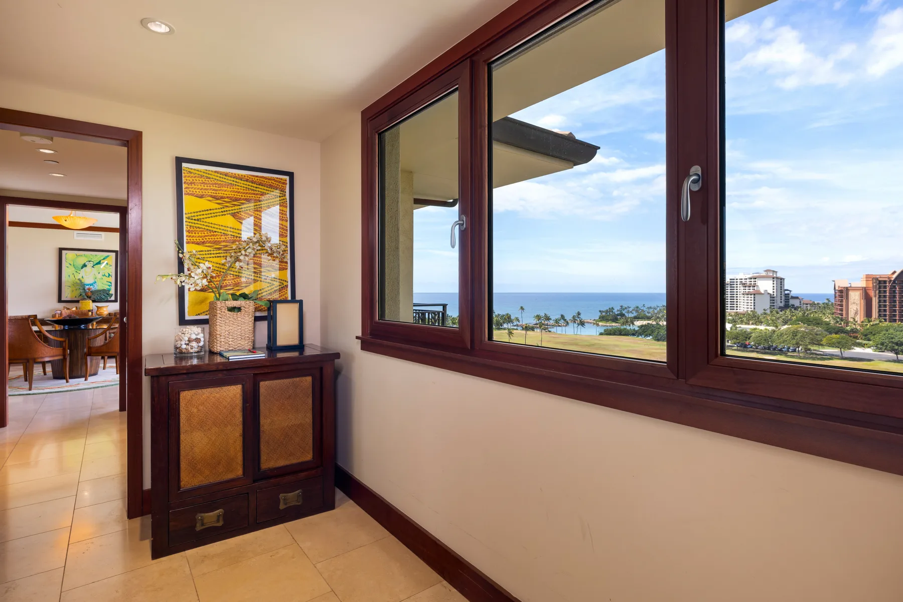 Una habitación luminosa con grandes ventanas que dan al mar y a edificios cercanos.