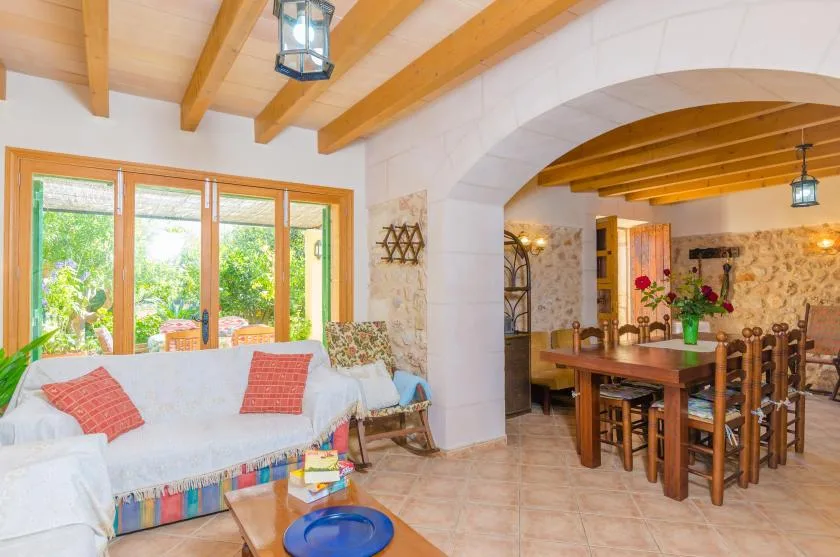 Una sala de estar y comedor con sofá, mesa de madera y ventanales.