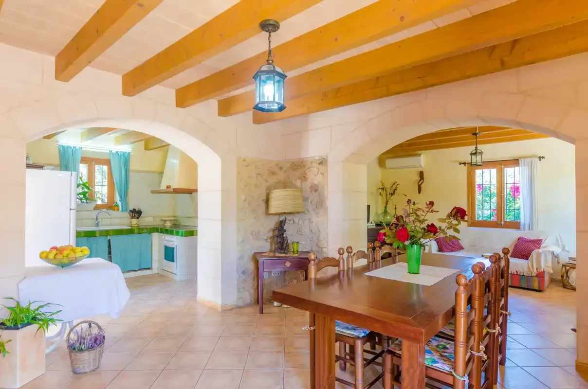Un comedor con una mesa de madera conecta con una cocina y una zona de estar.