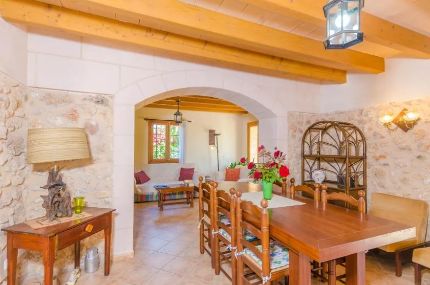 Un comedor con una mesa de madera y sillas bajo vigas vistas en el techo.