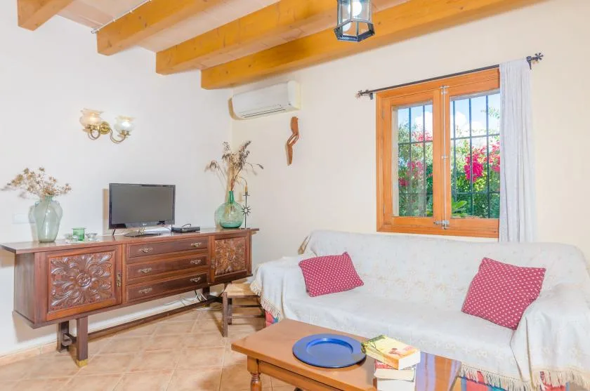 Una sala de estar con un sofá cubierto, un mueble de madera y un televisor.