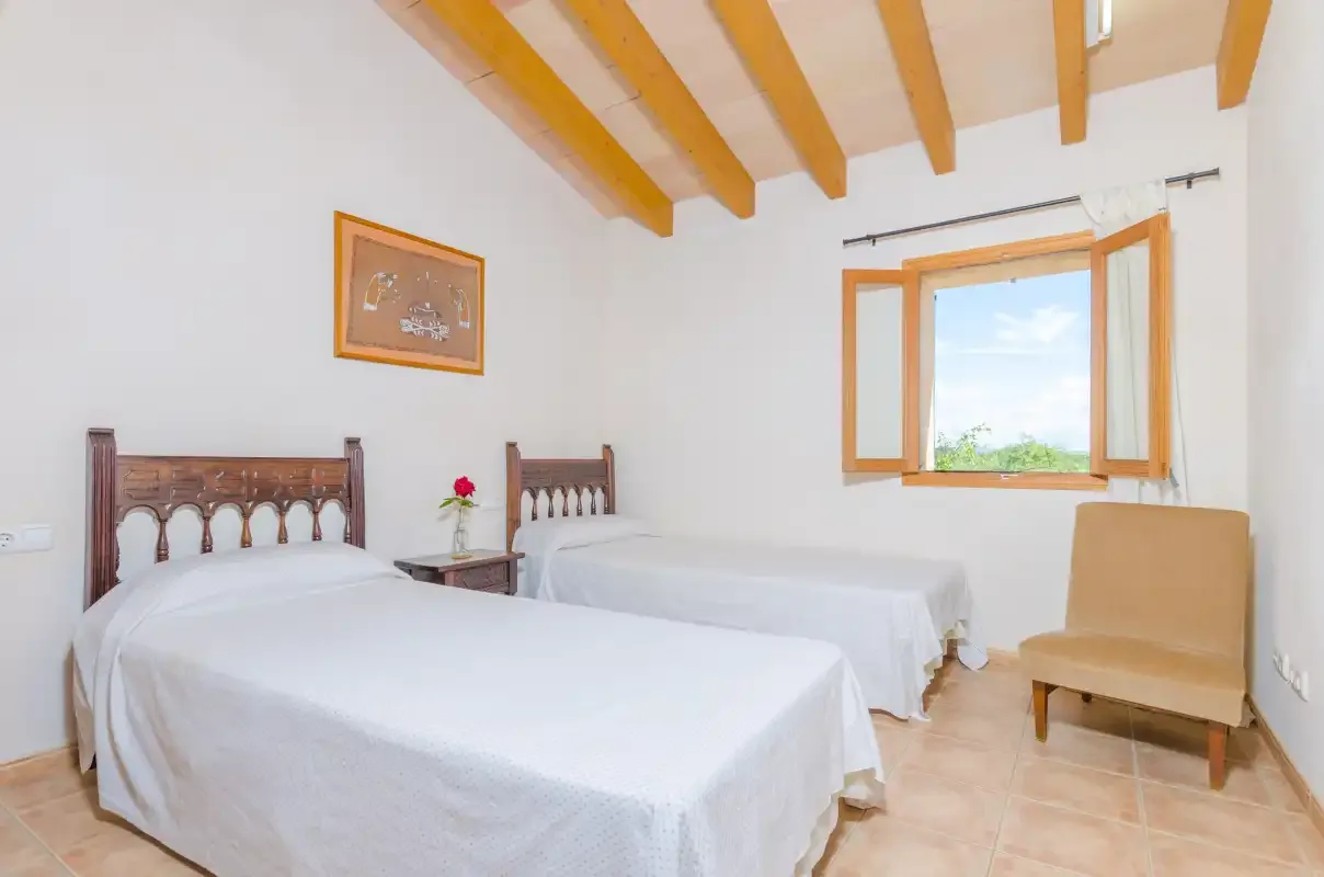 Un dormitorio luminoso con dos camas y una ventana abierta.
