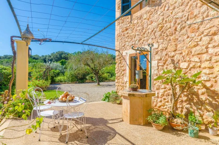 Un patio exterior con una mesa pequeña y asientos junto a un muro de piedra.