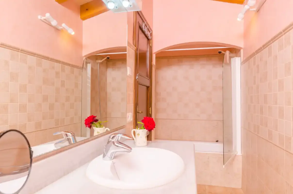 Un baño con lavabo, espejo y paredes de azulejos.