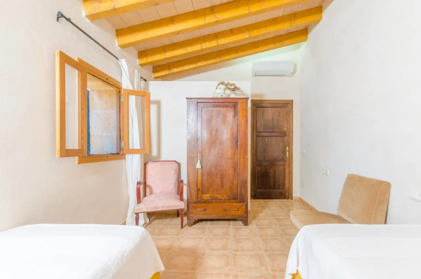 Un dormitorio con dos camas, armarios de madera y una ventana abierta.