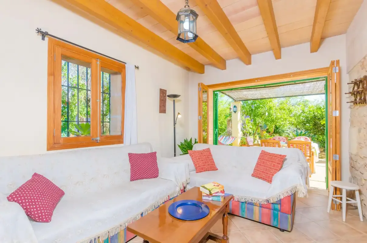 Una luminosa sala de estar con asientos alrededor de una mesa baja y vistas al jardín.
