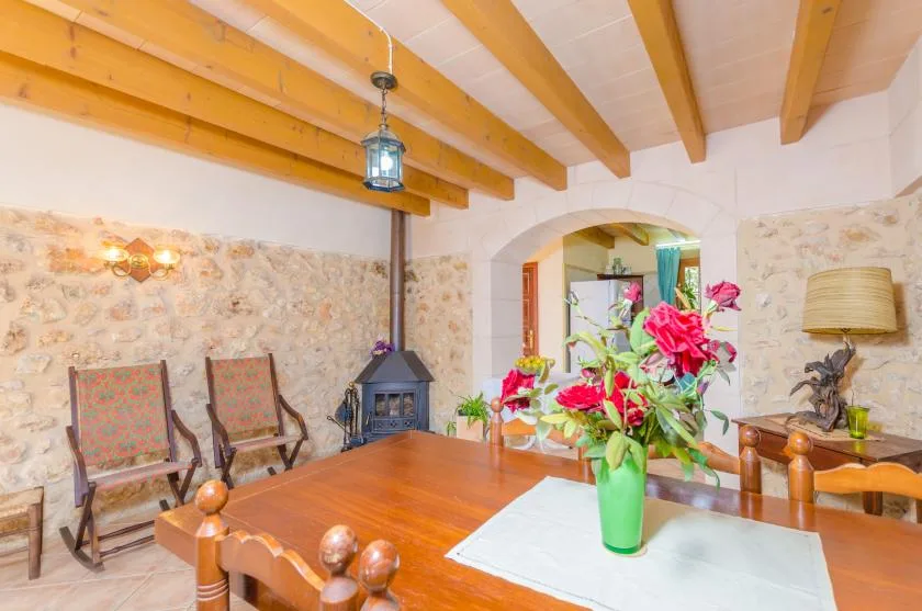 Un comedor con una mesa de madera, flores coloridas y vigas de techo expuestas.