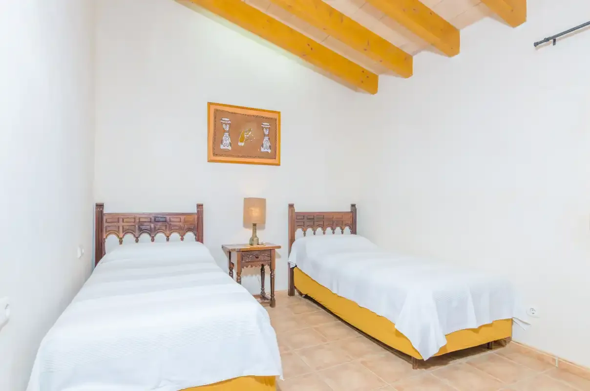 Un dormitorio con dos camas y vigas de madera a la vista.