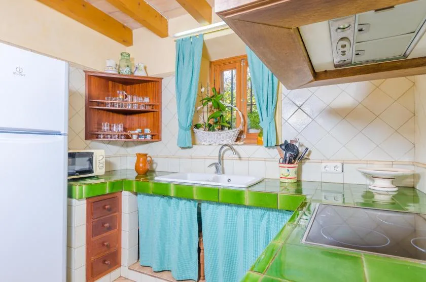 Una cocina compacta con encimeras verdes, un fregadero y una ventana sobre la encimera.