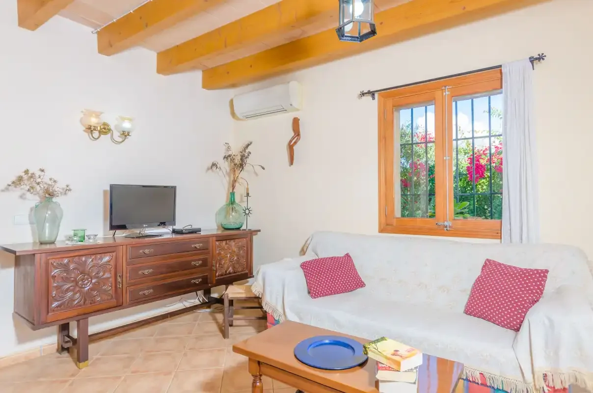 Una sala de estar con un sofá blanco y un mueble de madera bajo una ventana.