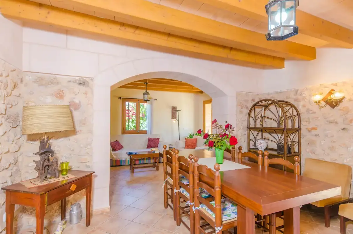 Un comedor con una mesa de madera y sillas bajo vigas de techo vistas.