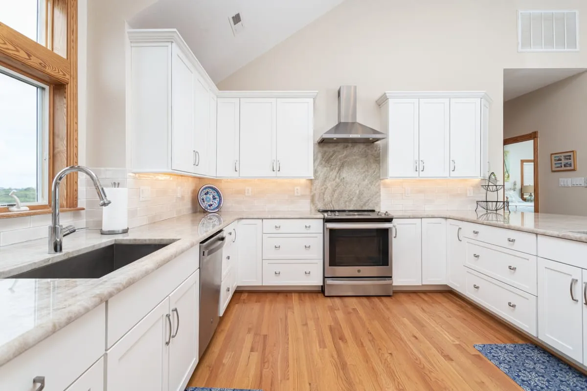 A bright kitchen with white cabinets, a central range, and wood flooring.