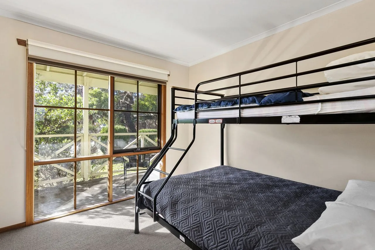 Un dormitorio con literas y una ventana grande con vistas a la vegetación.