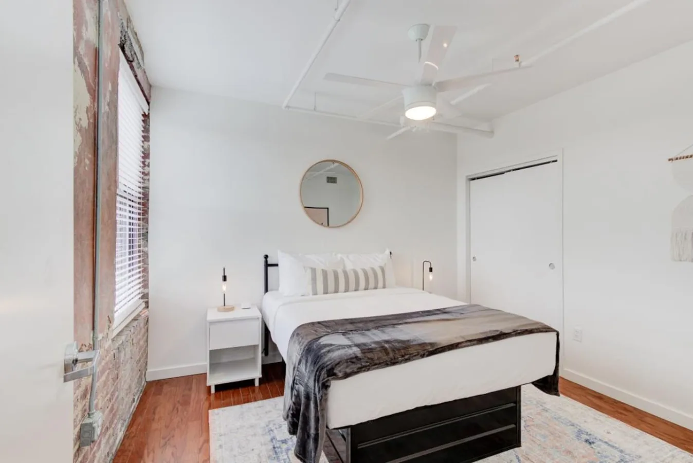 Un dormitorio luminoso con una cama bien hecha y un ventilador de techo.