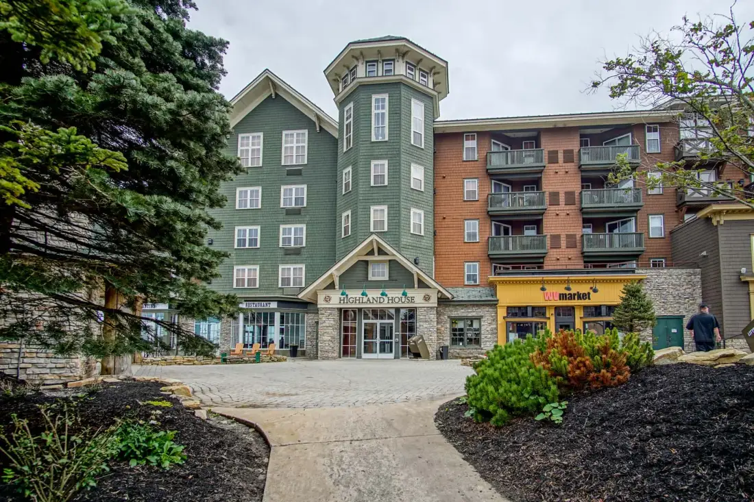 A multi-story building with green and brick facades stands beside a paved walkway.