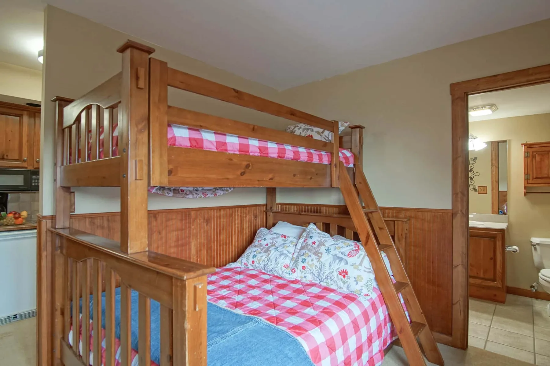 A bedroom with a wooden bunk bed and red-and-white checkered bedding.