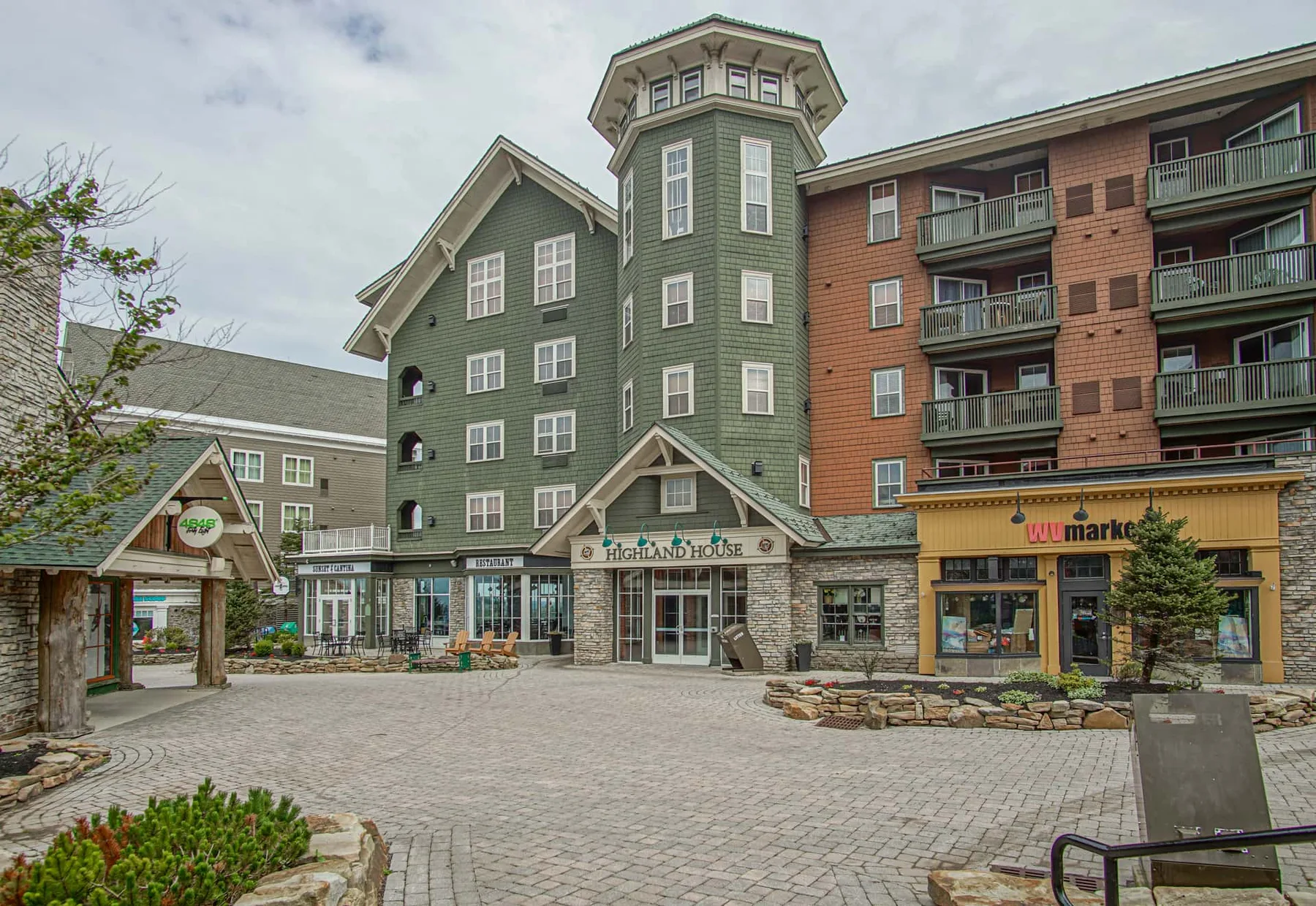 A paved plaza fronts a multi-story building with storefronts and balconies.