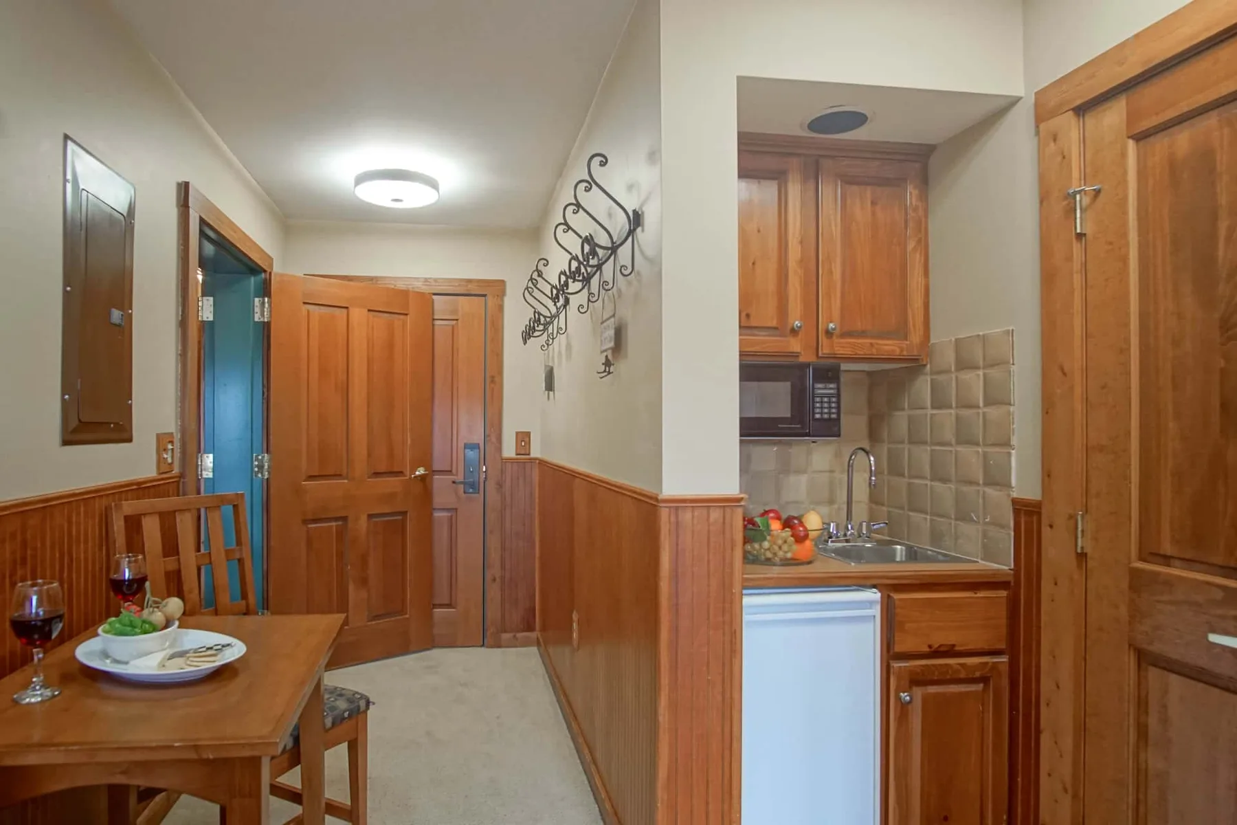 A narrow kitchen and dining area with wooden cabinets and a small table.