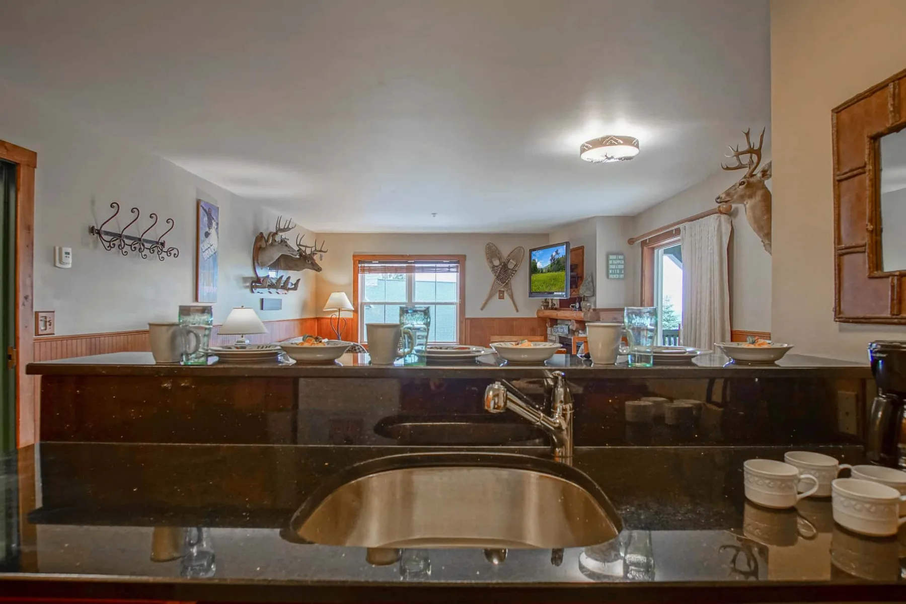 A dining area with a long counter, table settings, and mounted wildlife decor.