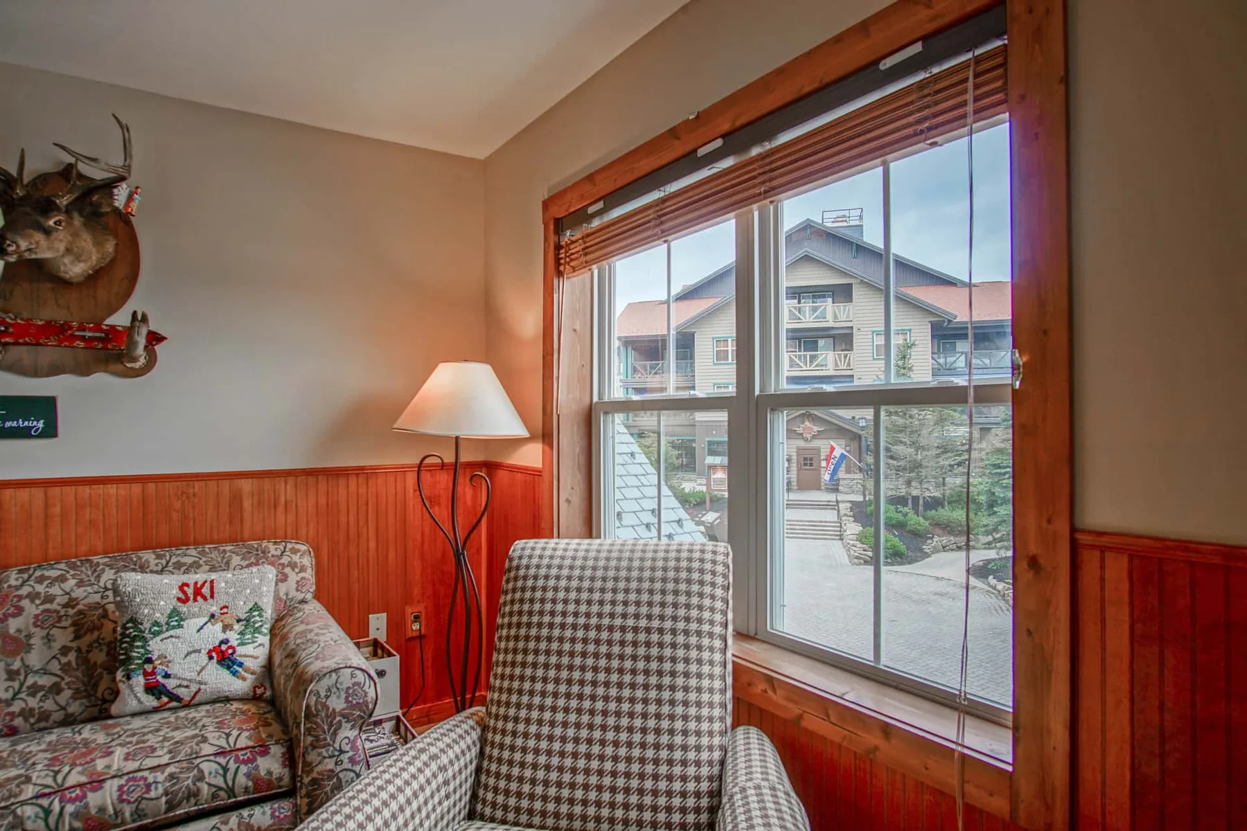 A sitting area with patterned seating beside a large window overlooking neighboring buildings.