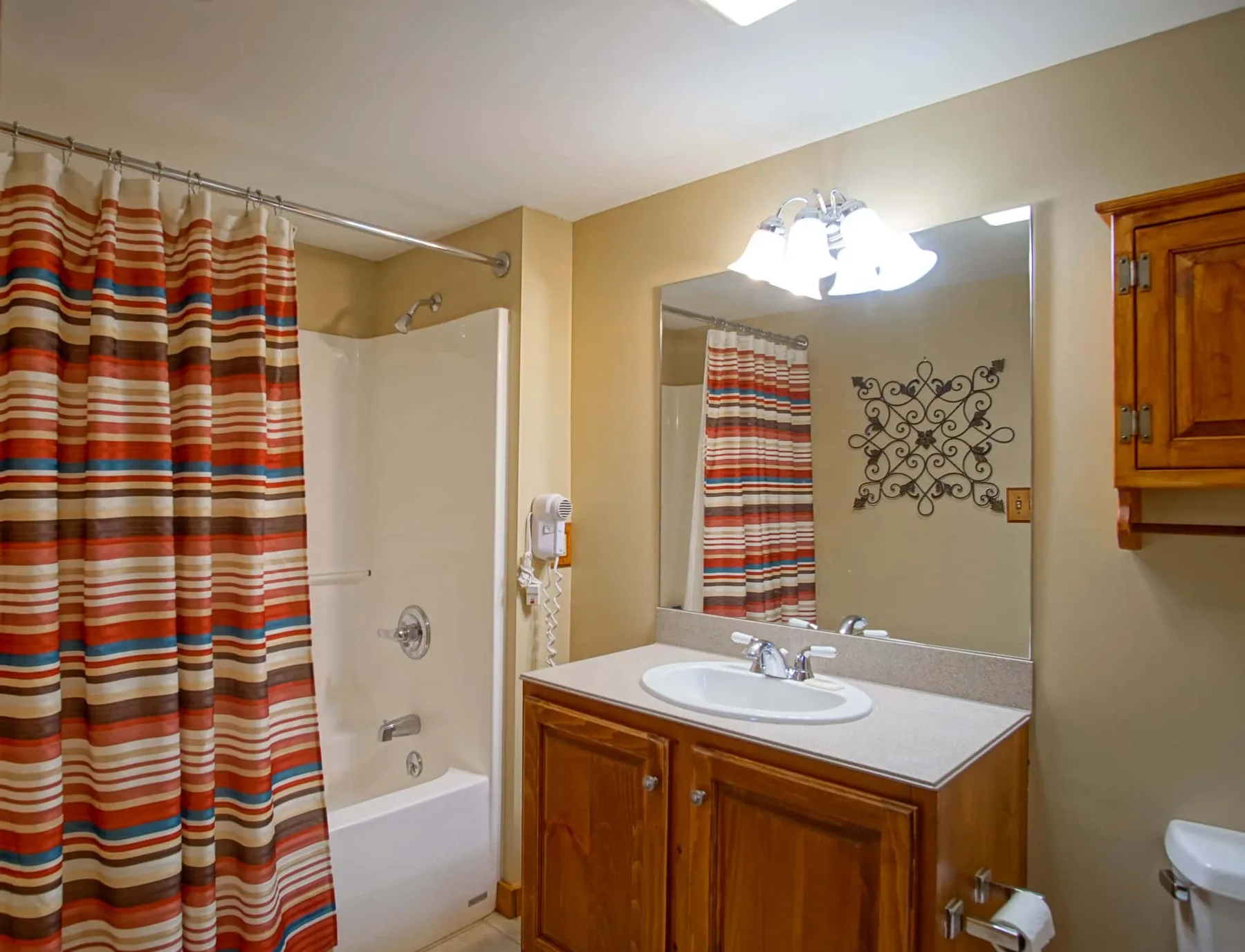 A bathroom with a striped shower curtain and a wooden vanity.