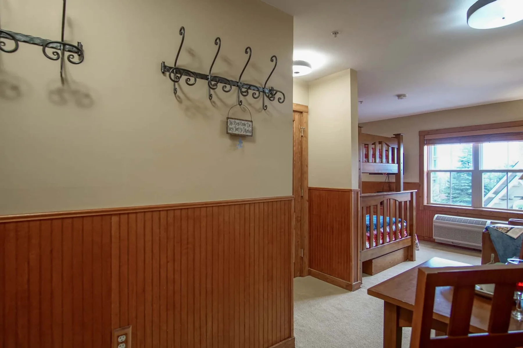 A wood-paneled hallway opens onto a seating area beside a window.