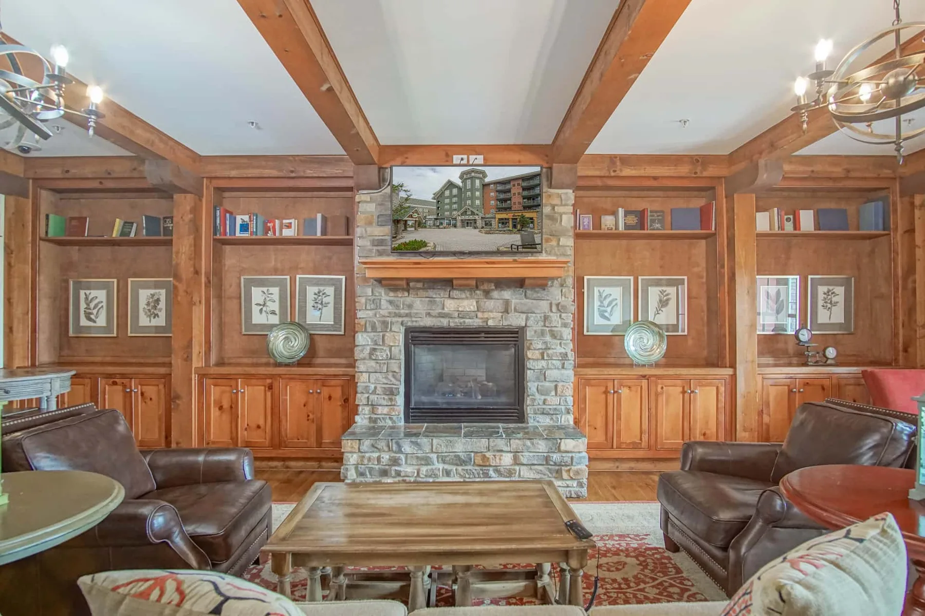 A wood-paneled living room centers on a stone fireplace, with leather seating and a coffee table.