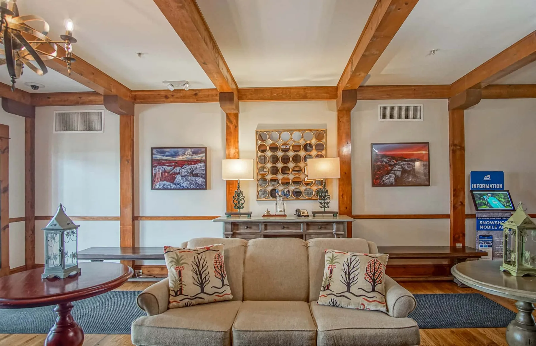 A lounge with cushioned seating, wooden ceiling beams, and framed wall art.